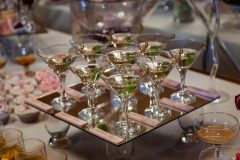 Glasses with martini and green olives stand on mirror tray